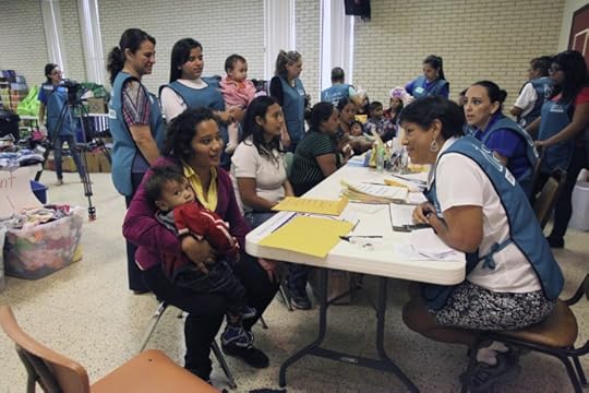 McAllen, TX, USA - July 8, 2014: A volunteer member of a Catholic Charities Disaster Response Team talks with a Central American refugee mother and child at the intake and orientation table of the reception hall of the Sacred Heart Catholic Church. Although volunteers came from various churches and denominations, Sacred Heart was the epicenter of the McAllen refugee assistance effort. (c) vichinterlang via iStock.