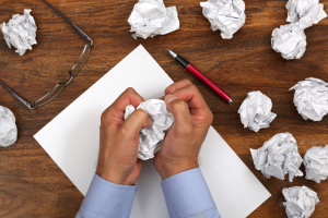 Crumpled paper and businessman tearing up another paper ball for the pile