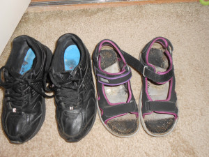 A pair of black tennis shoes and a pair of sandals.