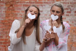 Girls holding hearts in front of mouths