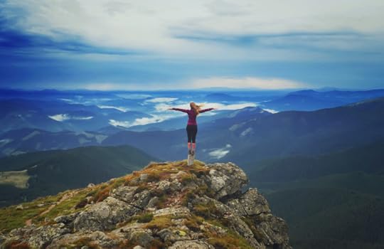 Young woman on a stone with raised hands
