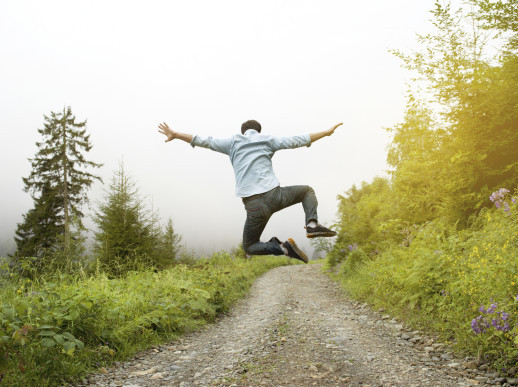Man jumping on a country road, rear view