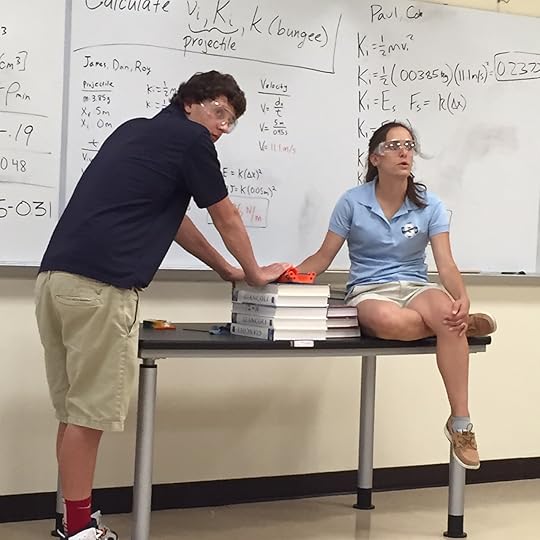 Teacher Kelly Searfoss prepares to launch a test projectile as a student holds the launching apparatus steady (check out the math on the whiteboards ... no math-o-phobia here!)