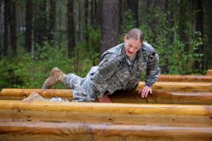 A woman soldier climbs across a horizonal ladder