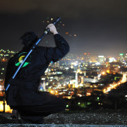 ninja assasin hold katana samurai old martial weapon swordat night with city lights in background