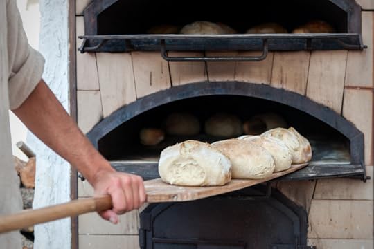 Baker using brick oven to bake bread.