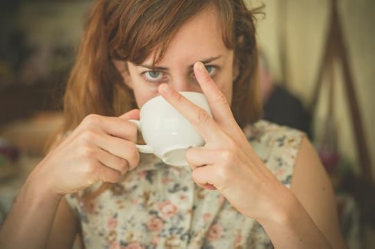 A young woman is drinking coffee and is displaying an obscene gesture with her fingers