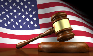 USA law and justice of The United States of America concept with a 3d render of a gavel on a wooden desktop and the flag of US on background.