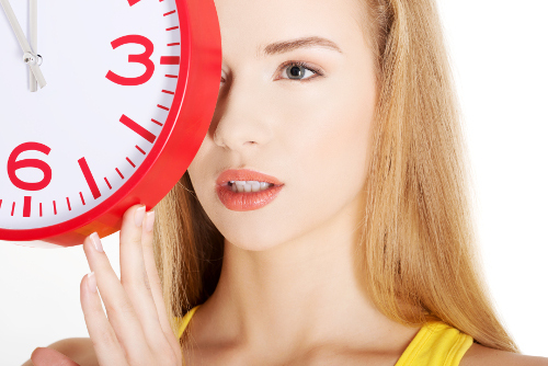 Happy young woman holding office clock