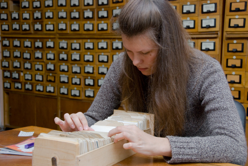Young woman searching file in the library card index.