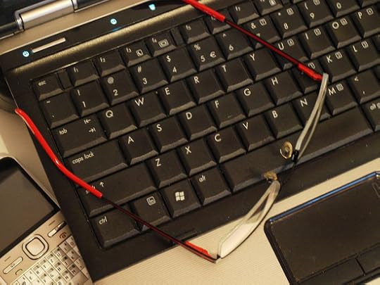 A black computer keyboard with red-framed glasses on top.