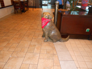 Dog sculpture with a red handkerchief over its face.