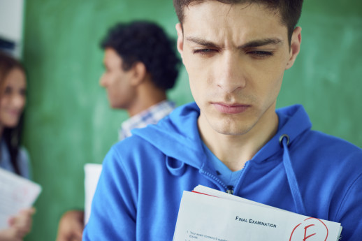 Frustrated student holding exam paper with bad mark