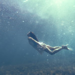 Underwater photo of a human diving in blue sea water