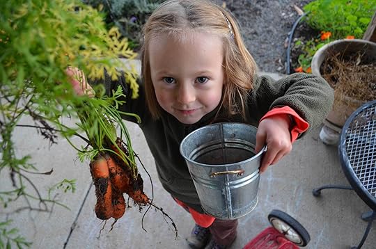 Juniper with some of her favorite veggies: a small bucket of cherry tomatoes and freshly pulled carrots