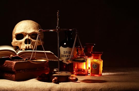 Human skull on old books near weight scales and ancient glass flasks