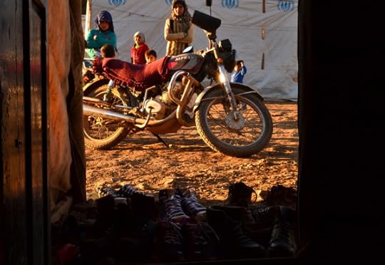 Women stand behind a motorcycle and in front of tents