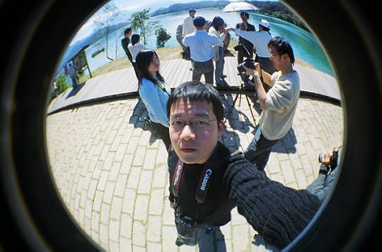 Man taking photo of himself while others take photos of each other in the background