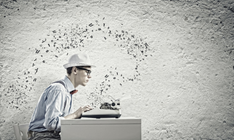Young funny man in glasses writing on typewriter