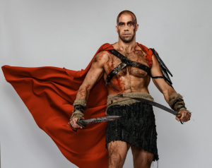 Wounded gladiator with two swords covered in blood isolated on grey