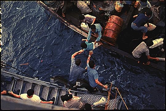 In the South China Sea, crewmen of the amphibious cargo ship USS Durham (LKA-114) take Vietnamese refugees aboard a small craft. The refugees will be transferred later by mechanized landing craft (LCM) to the freighter Transcolorado., 4/3/1975. General Records of the Department of the Navy, National Archives Identifier 558518
