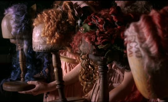 Four wigs of various colors and shapes on wigstands.