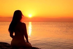 stock-footage-silhouette-of-a-woman-sitting-on-a-beach-at-sunset1-e1336944377218