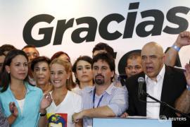 Jesus Torrealba (R), secretary of the Venezuelan coalition of opposition parties (MUD), speaks near Lilian Tintori (2nd L), wife of jailed Venezuelan opposition leader Leopoldo Lopez during a news conference in Caracas December 7, 2015. Venezuela's opposition won control of the legislature from the ruling Socialists for the first time in 16 years on Sunday, giving them a long-sought platform to challenge President Nicolas Maduro. The banner reads, 