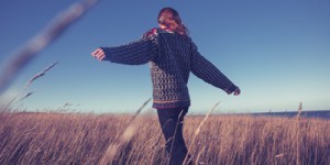 Young woman spinning around in meadow by the sea