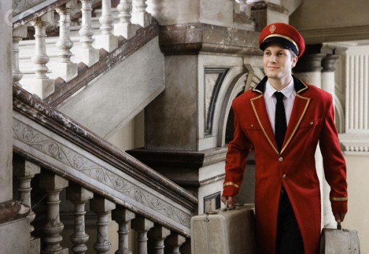 Bellhop carrying suitcases up stairs --- Image by © Olix Wirtinger/Corbis