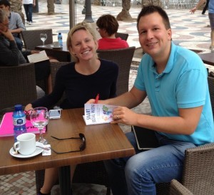 #1 INTERNATIONAL best selling author Lasse Rouhiainen signing a copy of his book Smart Social Media. He is sitting at a table with a woman beside him.
