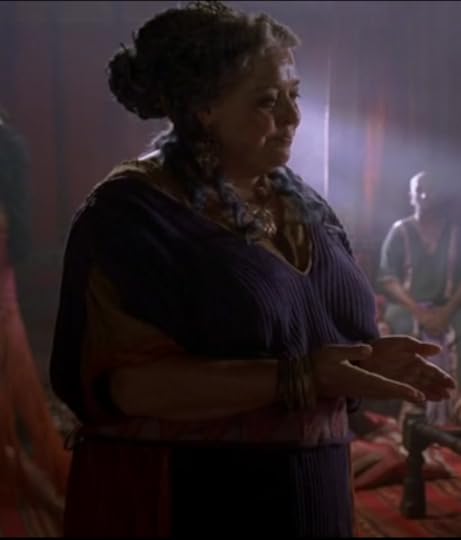 A large woman in a gray-to-purple ombre wig and bright purple, ribbed dress.