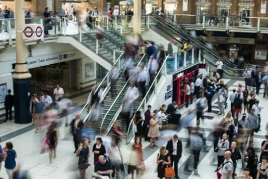 A time-lapse photo of people milling about an interior with stairs and an escalator.