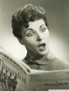 Shocked woman reading newspaper in studio, (B&W), portrait