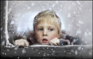 child-looking-through-window-in-snow