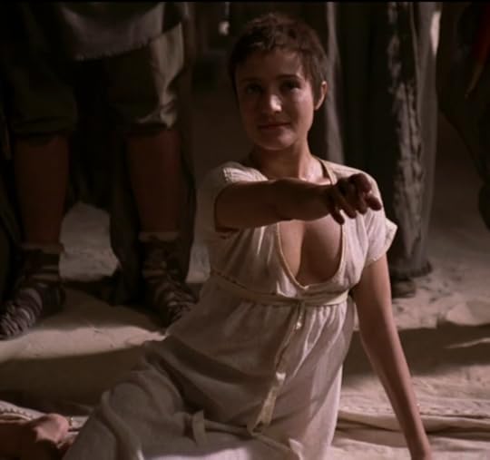 An elfin white girl wearing a very low-cut linen gown with an empire waist and short sleeves.