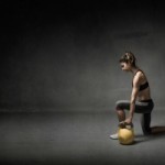 girl with kettlebell on hand, dark background