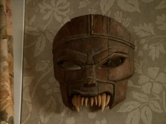 A wooden mask with angry eyes and sharp teeth