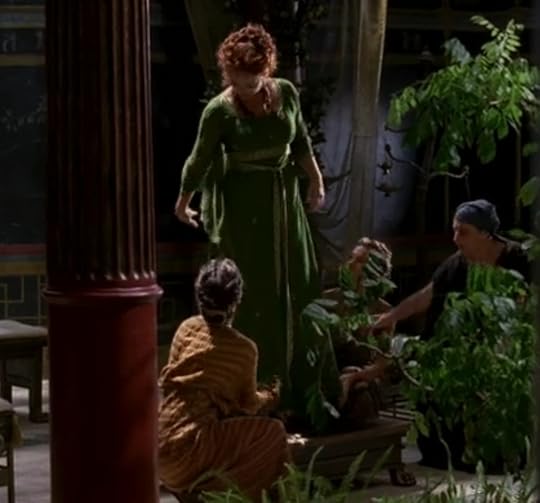 Atia wearing a bright green dress with long sleeves and a fitted waist, with ribbon girdles around it.