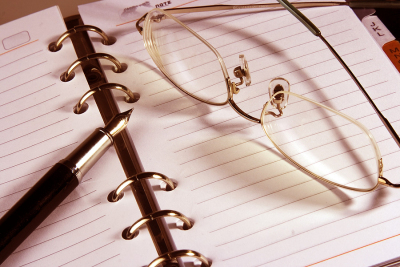 An open tablet, pen, and a pair of glasses