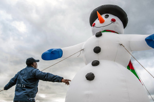 A Navy petty officer looks up at inflatable snowman.