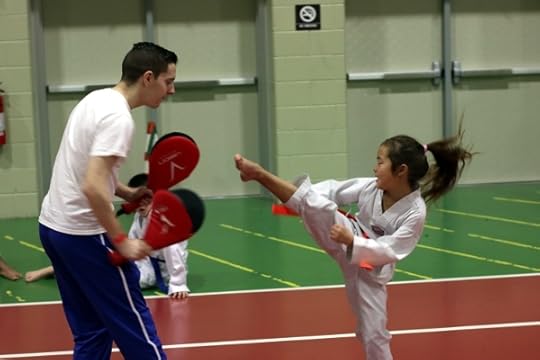 SteelyKid doing a round kick while warming up at the taekwondo tournament.