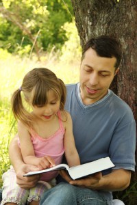 young father with a small daughter reading the Bible
