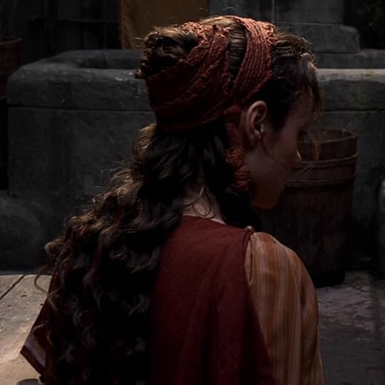 Eirene has long brown hair that's curly, and she's wearing what look likes a long strip of gauze wrapping around her hair like multiple headbands.