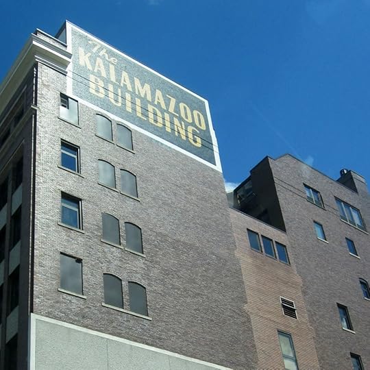 A row of brown brick buildings, one of which is painted with a huge sign that says