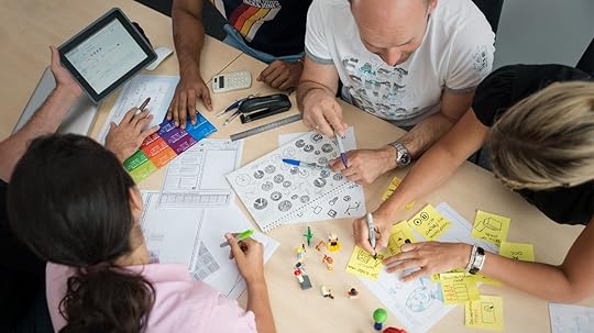 People working around a desk with a variety of different drawing tools.