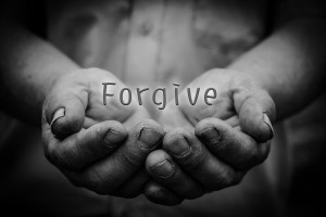 Forgive text is in the holding hands with dark corners.