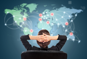 Attractive brunette young woman in futuristic interface sitting in front of world map with glowing hot points location and connection lines.