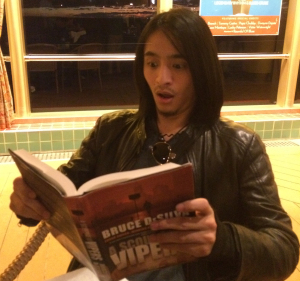 Blues singer and guitarist Shun Ng reading Bruce DeSilva's novel, 