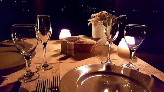 An elegantly set table with flowers and candles on it, with a dark night in the background.